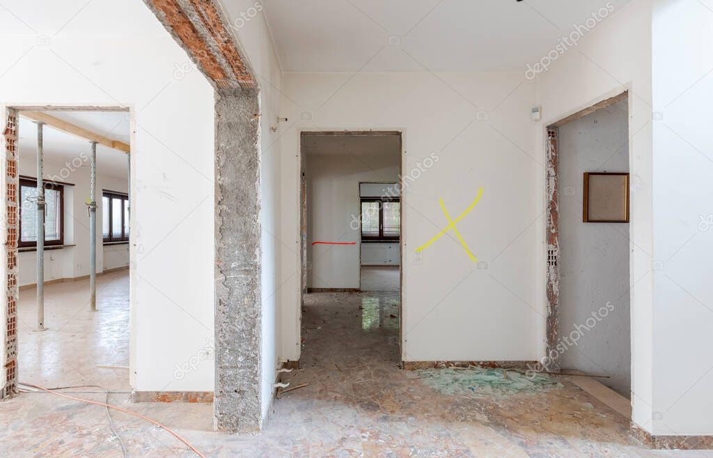 Large room with props fixed to the ceiling of an old villa undergoing demolition and renovation. There is a lot of dirt and dust. Nobody inside