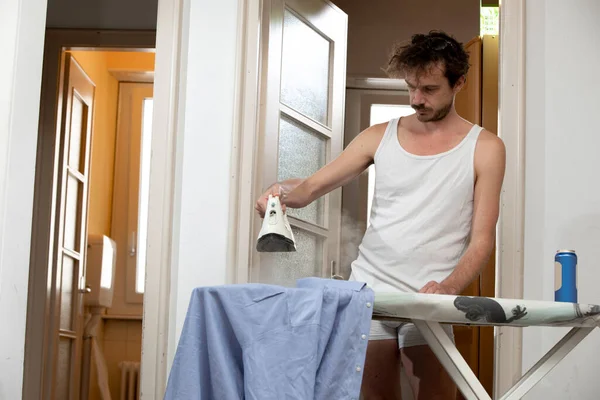 Joven Hombre Guapo Solo Pasillo Casa Planchando Una Camisa Azul — Foto de Stock