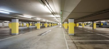 Önde boş bir yer altı süpermarketi var. Yerde sarı beton kolonlar ve beyaz ok var. Boşluğu kopyala
