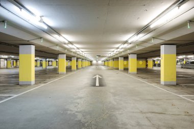 Önde boş bir yer altı süpermarketi var. Yerde sarı beton kolonlar ve beyaz ok var. Boşluğu kopyala