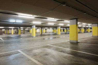 Arabalar için sarı beton sütunları ve beyaz çizgileri olan boş bir yer altı süpermarketi. Boşluğu kopyala