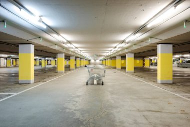 Önde boş bir yer altı süpermarketi var. Yerde sarı beton kolonlar ve beyaz ok var. Boşluğu kopyala