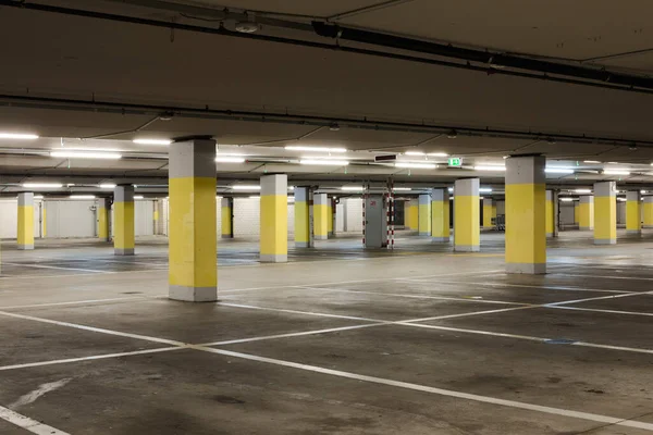 Arabalar için sarı beton sütunları ve beyaz çizgileri olan boş bir yer altı süpermarketi. Boşluğu kopyala