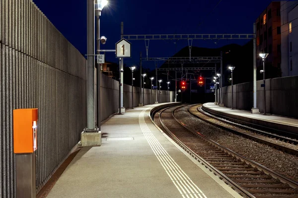 晚上在荒无人烟的瑞士一个火车站的前景 火车轨道在黑暗中结束 里面没有人 — 图库照片