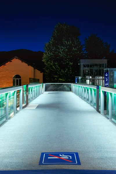 Yaya köprüsünün önü yeşil ışıklarla aydınlatılmış. Yerde sigara içilmesine izin verilmeyen bir işaret var. İçeride kimse yok.