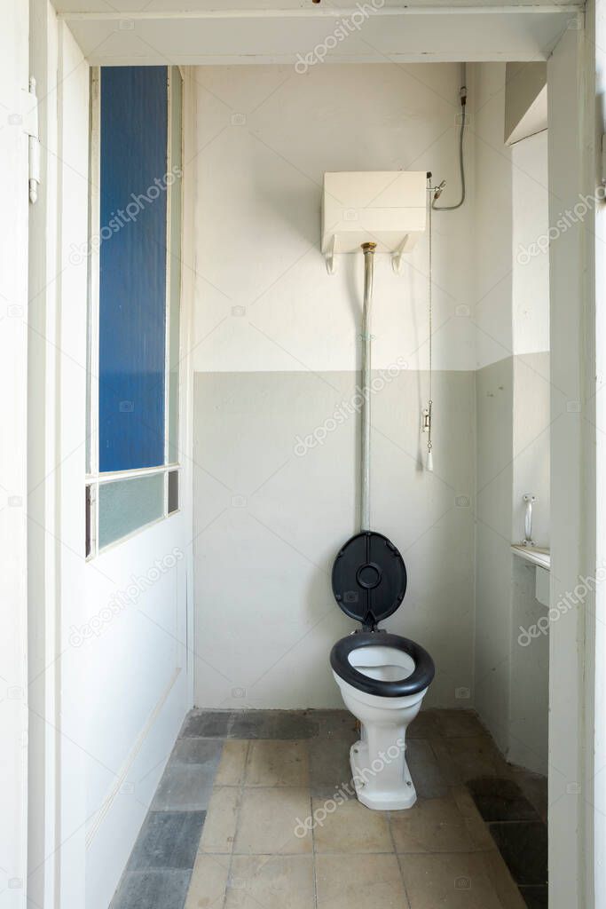 Front view of the toilet room with blue toilet board. On the left is a blue window. Interior of an abandoned villa to be restored.