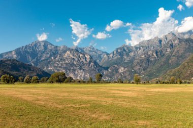 Panoramic view of a meadow with alpine mountains in the background. Spluga Pass, border between Italy and Switzerland