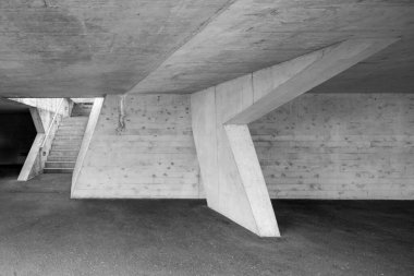 Underpass of a reinforced concrete car park. An empty staircase with a light coming from above
