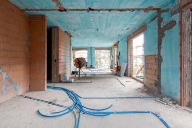 Mavi duvarları, yerde elektrik boruları ve yeni döşenmiş turuncu tuğlaları olan eski bir villanın içi. İçeride kimse yok.