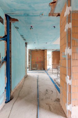 Mavi duvarları, yerde elektrik boruları ve yeni döşenmiş turuncu tuğlaları olan eski bir villanın içi. İçeride kimse yok.