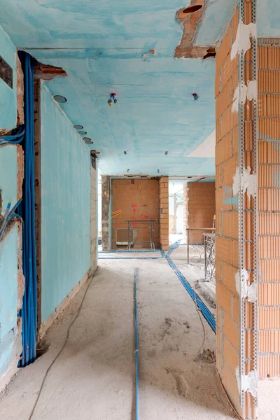 Interior of an ancient villa under renovation with blue painted walls, electrical pipes on the ground and freshly laid orange bricks. Nobody inside