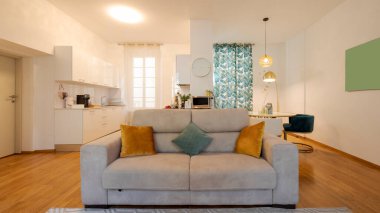 Zarif bir dairede modern bir açık alan. Ön tarafta rahat bir kanepe, yemek odası ve arkada da mutfak var. İçeride kimse yok.