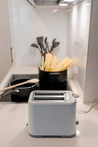 鍋の後ろにパスタを入れたモダンな白いキッチンでトースターの詳細 清潔でエレガントなキッチン 正面図 — ストック写真
