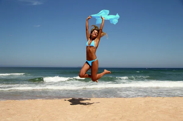 Beautiful tanned woman jumping on beach — Stock Photo, Image