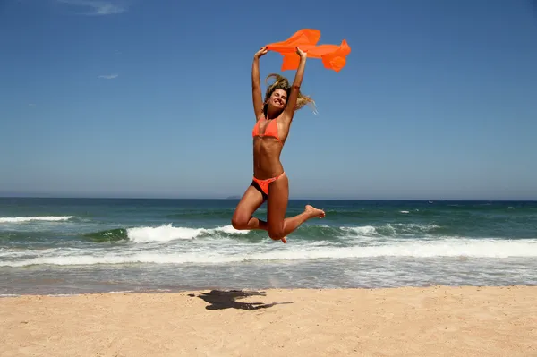 Schöne gebräunte Frau springt am Strand lizenzfreie Stockfotos