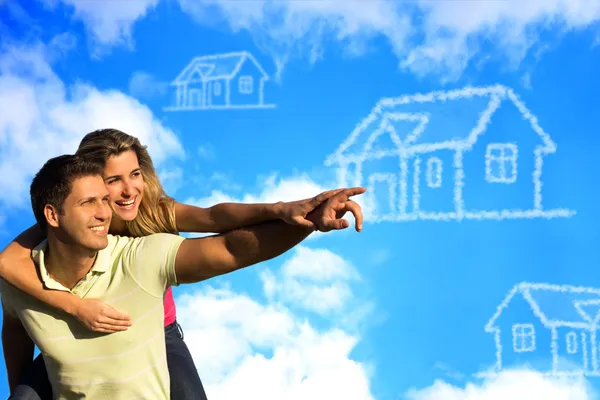 Glückliches Paar unter blauem Himmel, das von einem Haus träumt. lizenzfreie Stockbilder