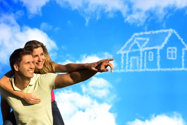 Glückliches Paar unter blauem Himmel, das von einem Haus träumt. Stockbild