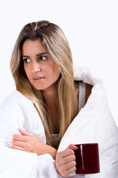 genç kadın bir kupa holding beyaz battaniye altında