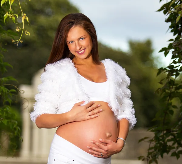 Красивая беременная женщина стоит и трогает живот — стоковое фото