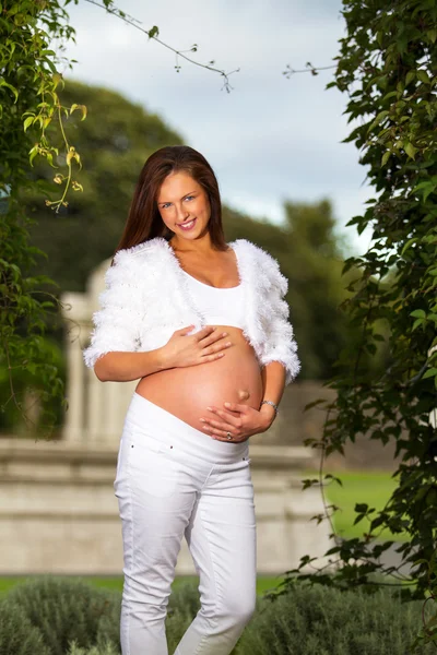 Beautiful pregnant woman standing and touching her belly — Stock Photo, Image