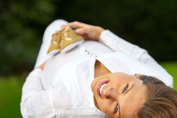 Porträt schwangere Frau liegt im Gras — Stockfoto