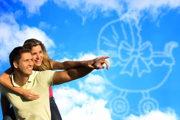 Happy couple dreaming of a baby and pointing to clouds. — Stock Photo, Image