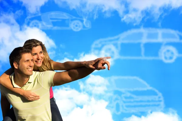 Casal apontando para nuvens em forma de carros — Fotografia de Stock