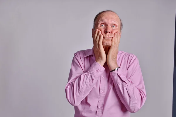 Senior man with crossed eyes and hands on cheeks — Stock Photo, Image