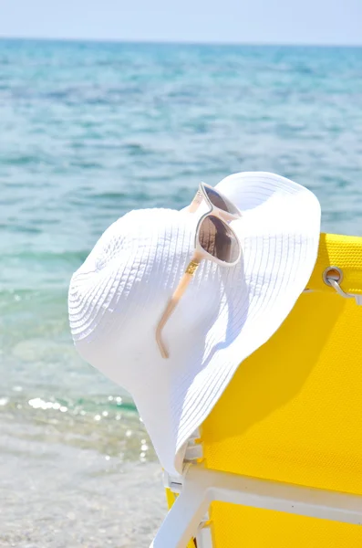 Gelbe Sonnenliege mit weißem Hut darauf mit Meereshintergrund — Stockfoto