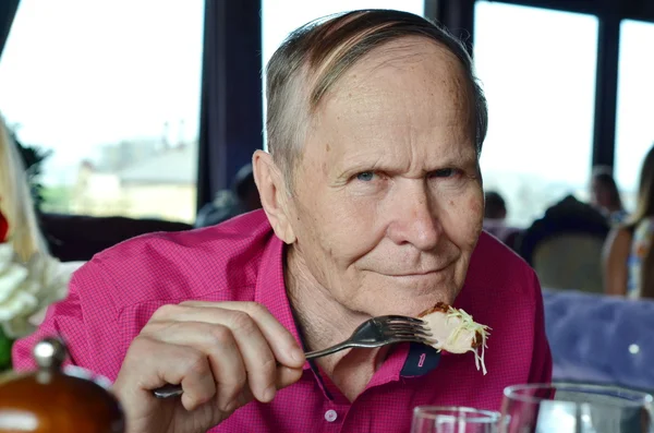 Portrait of senior man eating in a restaurant — Stock Photo, Image