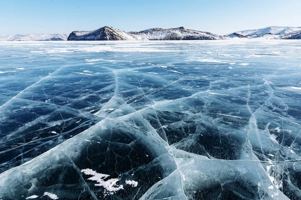 Lago Baikal, lago congelado, hielo con grietas y colinas bancarias en el fondo. Fotos de stock libres de derechos