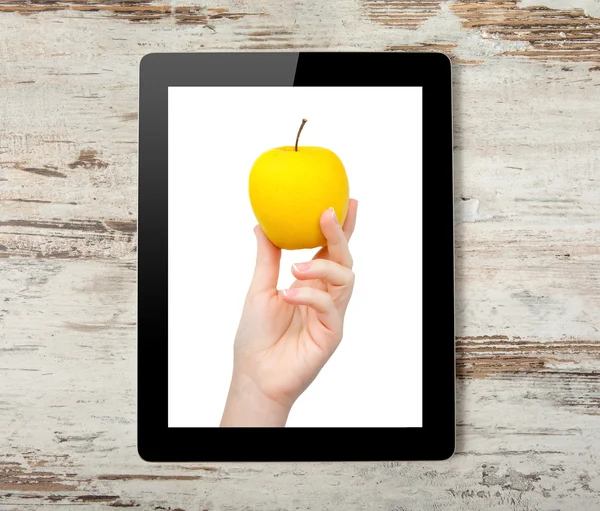 Tablet computer with the hand and a yellow apple on the screen — Stock Photo, Image