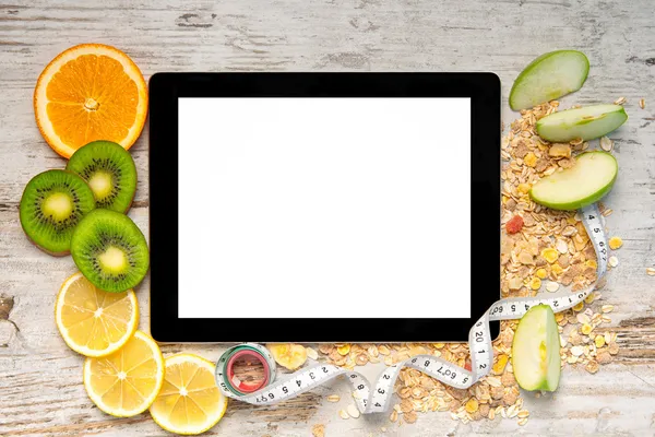 Tablet computer with fruit and a measuring tape for weight loss — Stock Photo, Image