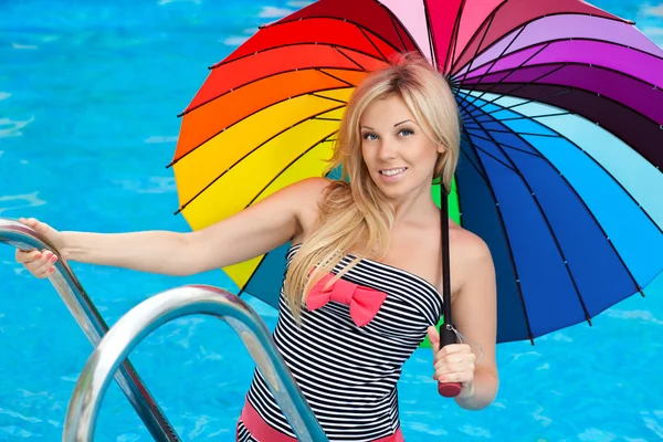 Menina bonita à beira da piscina com guarda-chuva colorido — Fotografia de Stock