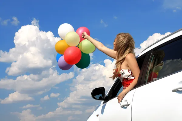Porträt eines Mädchens im Auto mit bunten Luftballons — Stockfoto
