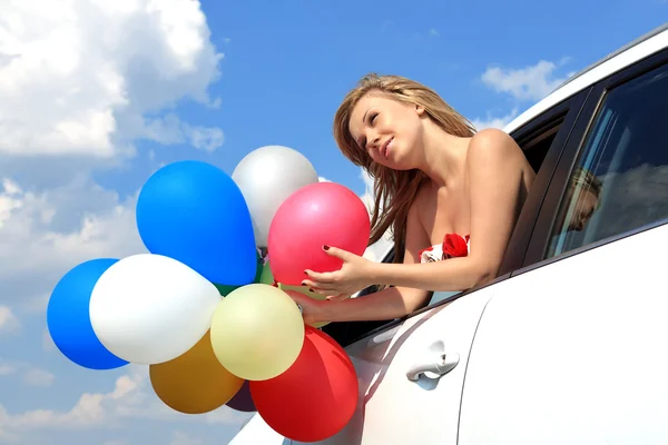 Retrato uma menina no carro com balões coloridos — Fotografia de Stock