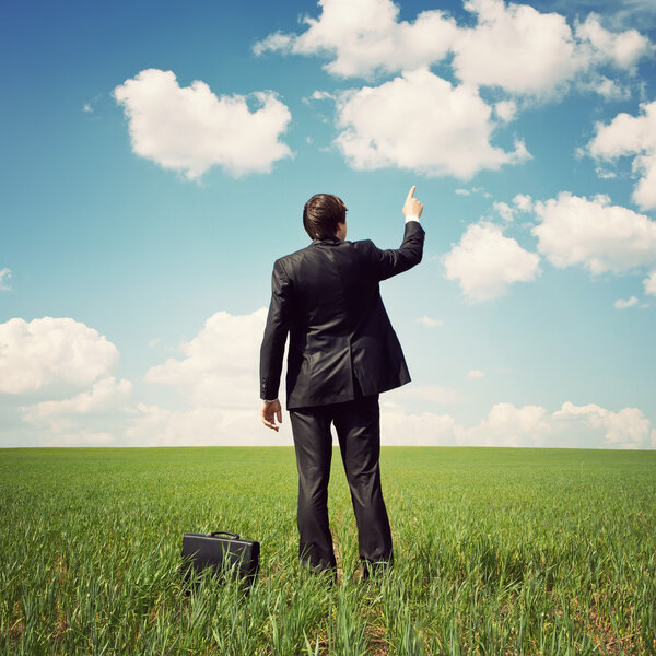 businessman standing in the field and points a finger at something