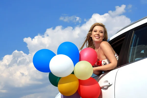 Retrato de uma menina no carro com balões coloridos — Fotografia de Stock