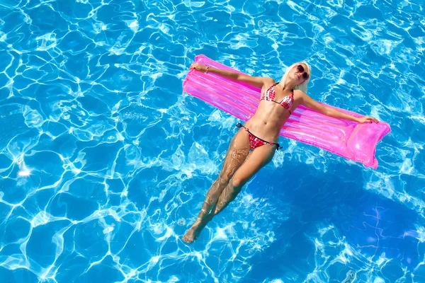 Sexy girl floating on a mattress in the sea or swimming pool — Stock Photo, Image