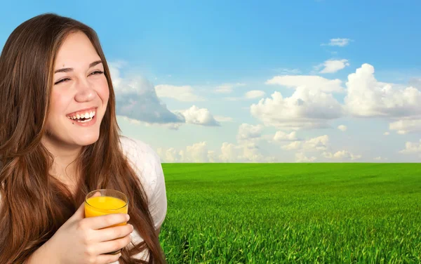 Vacker flicka håller ett glas saft och leende på backg — Stockfoto