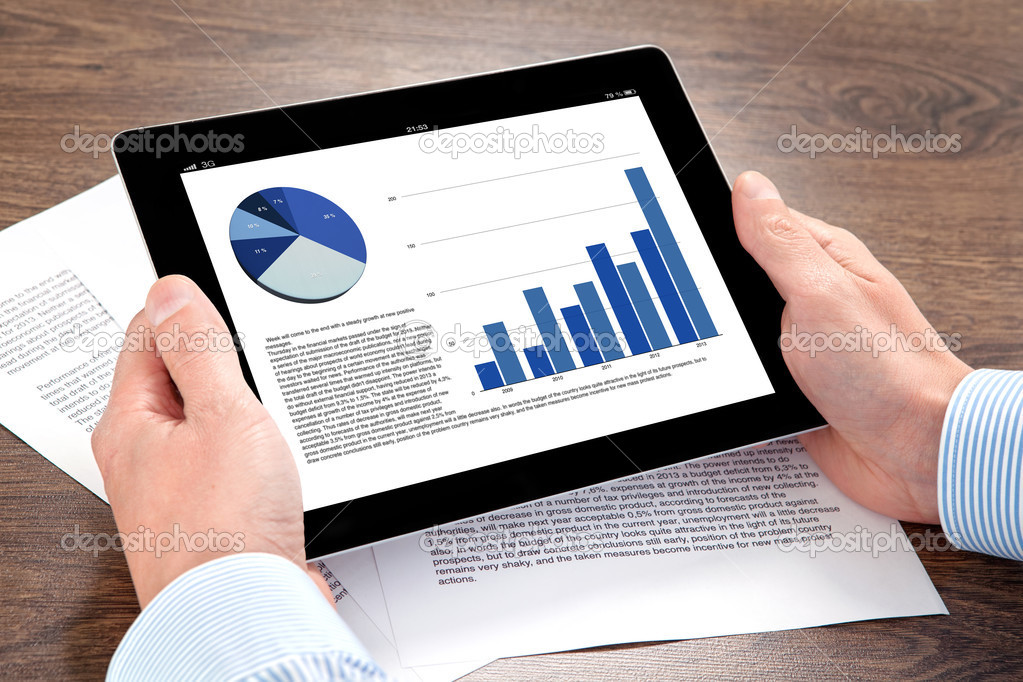 businessman holding a tablet with graphics on a screen on the ta