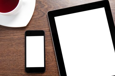 tablet and phone with isolated screen lie on a wooden table with
