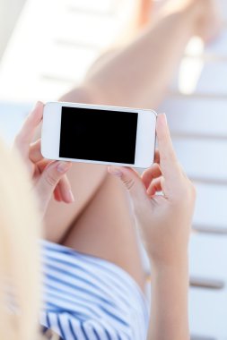 dokunmatik telefon ile bir şezlong üzerinde yatan bir mayo içinde kız