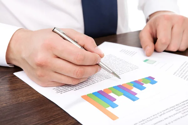 Businessman in the office of the table points to the graphics — Stock Photo, Image