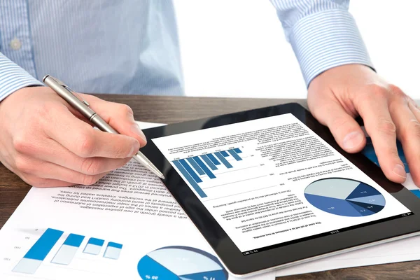 Businessman holding a tablet with graphics on a screen on the t — Stock Photo, Image