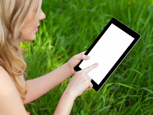 Kız bir tablet yeşil çim bir arka plan üzerinde tutar. — Stok fotoğraf