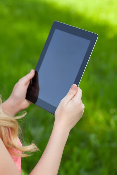 Dziewczyna trzyma tabletkę na tle zielonej trawie — Zdjęcie stockowe