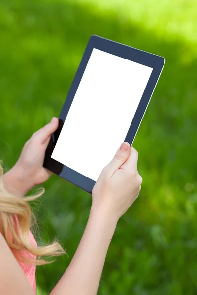 Meisje houdt een tablet op een achtergrond van groen gras — Stockfoto