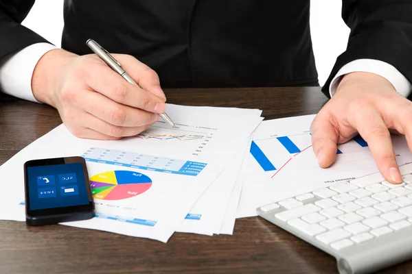 Businessman in the office of the table with graphics and phone — Stock Photo, Image