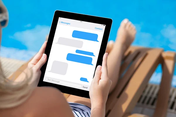 Girl lying on a sun lounger by the pool with a computer tablet w — Stock Photo, Image
